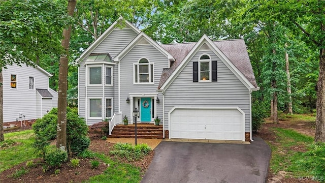 view of front of house with asphalt driveway, a garage, and a shingled roof