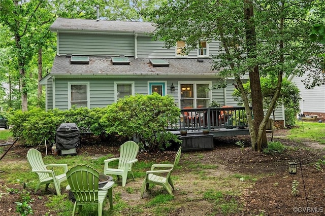 rear view of property with a wooden deck and a fire pit
