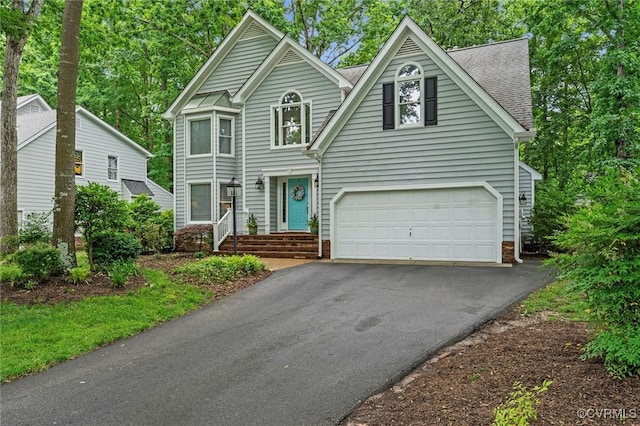 traditional-style home with asphalt driveway, a garage, and a shingled roof