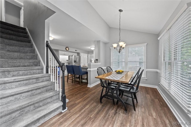 dining area with stairway, dark wood finished floors, vaulted ceiling, a chandelier, and baseboards