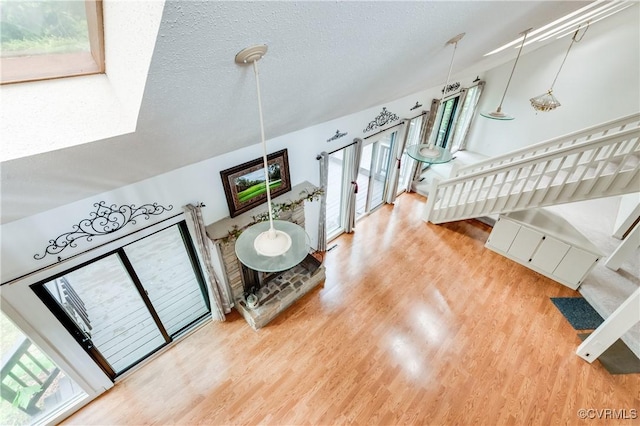 living area with wood finished floors, healthy amount of natural light, stairway, and a textured ceiling