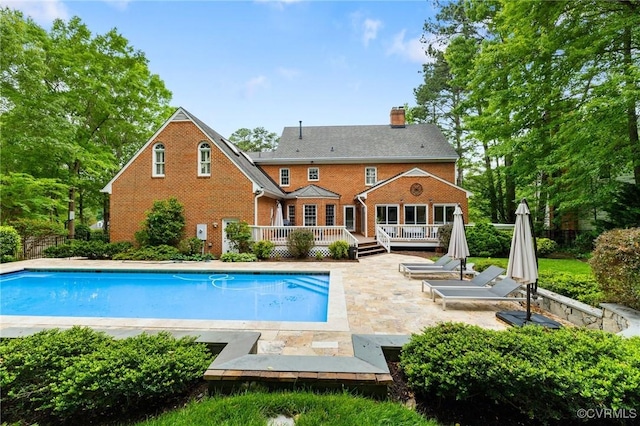 11458 Barrington Bridge Ct, Henrico, VA 23233 - rear view of house with a wooden deck, brick siding, a chimney, and an outdoor pool