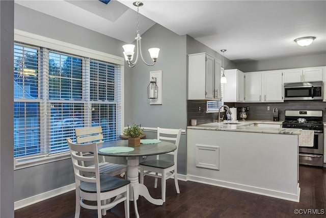 kitchen with stainless steel appliances, a chandelier, backsplash, dark wood finished floors, and white cabinets