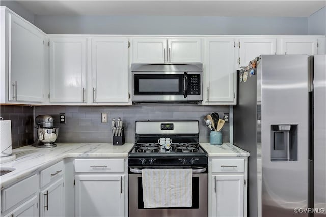 kitchen with appliances with stainless steel finishes, white cabinetry, and backsplash