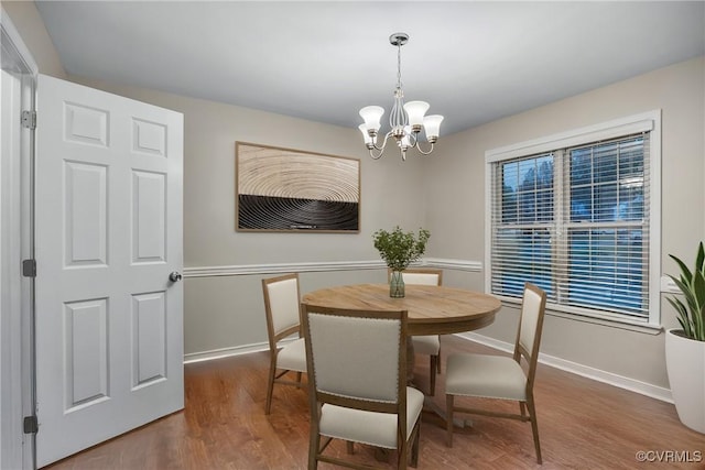 dining room featuring a chandelier, wood finished floors, and baseboards