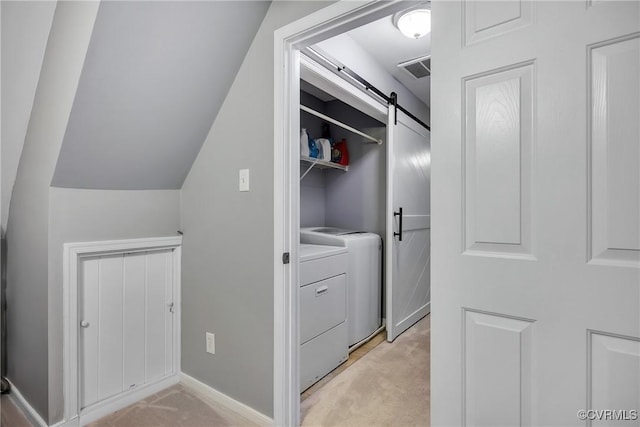 washroom featuring washing machine and dryer, light colored carpet, and a barn door