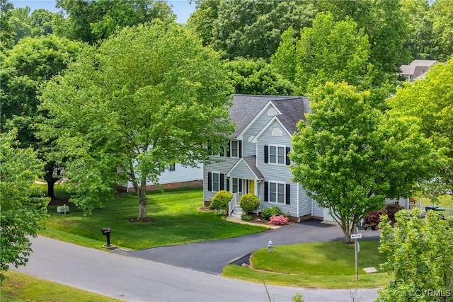 view of front of property with driveway, a front yard, and a shingled roof