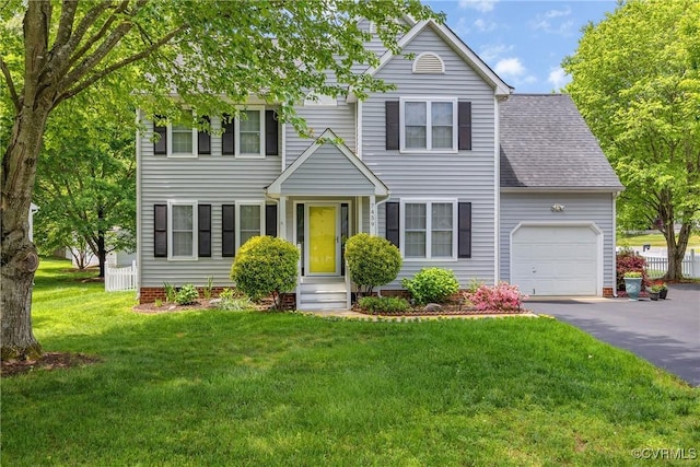 view of front of house featuring an attached garage, asphalt driveway, a front yard, and a shingled roof