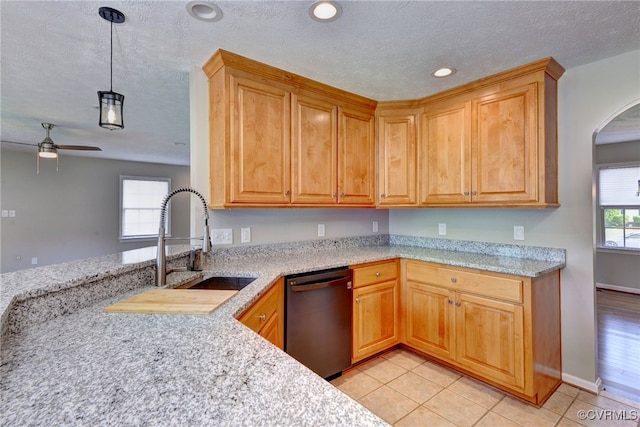 kitchen with dishwasher, a sink, light stone countertops, a textured ceiling, and ceiling fan