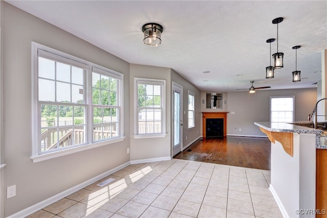 kitchen featuring healthy amount of natural light, ceiling fan, baseboards, and pendant lighting