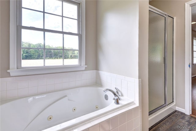 full bath with a shower stall, a jetted tub, wood finished floors, and baseboards