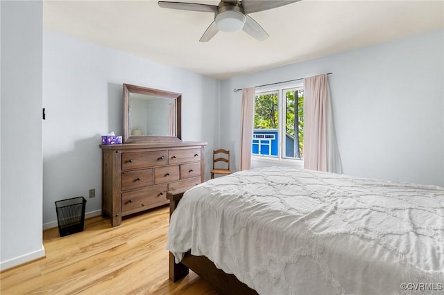 bedroom with light wood finished floors, baseboards, and a ceiling fan