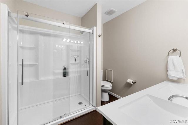 full bath featuring toilet, a stall shower, and vanity