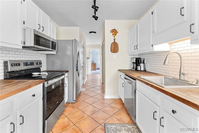 kitchen featuring stainless steel appliances, wood counters, a sink, and light tile patterned flooring