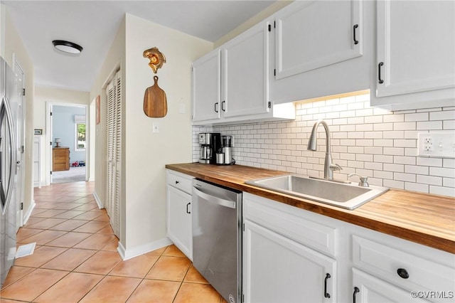 kitchen featuring butcher block counters, dishwasher, a sink, backsplash, and light tile patterned floors