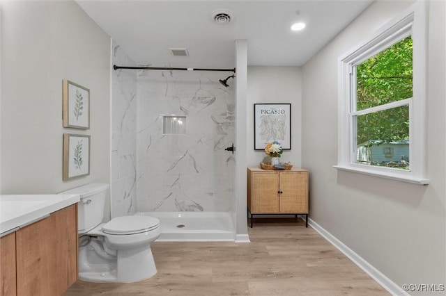 full bathroom featuring vanity, a marble finish shower, toilet, wood finished floors, and baseboards