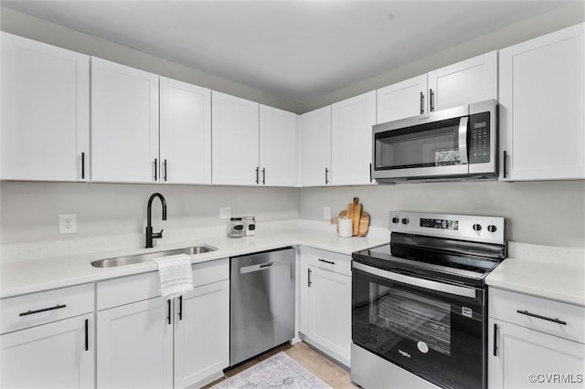 kitchen featuring appliances with stainless steel finishes, a sink, and white cabinets