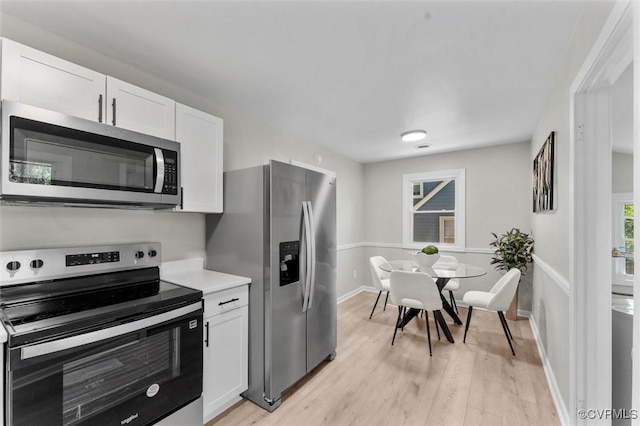 kitchen featuring stainless steel appliances, white cabinets, light countertops, light wood-style flooring, and baseboards