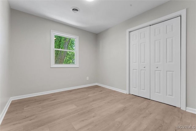 unfurnished bedroom with light wood-style floors, baseboards, and a closet