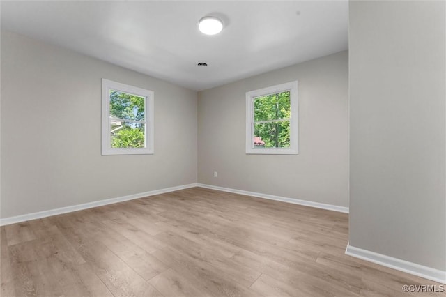 unfurnished room with healthy amount of natural light, light wood finished floors, and baseboards