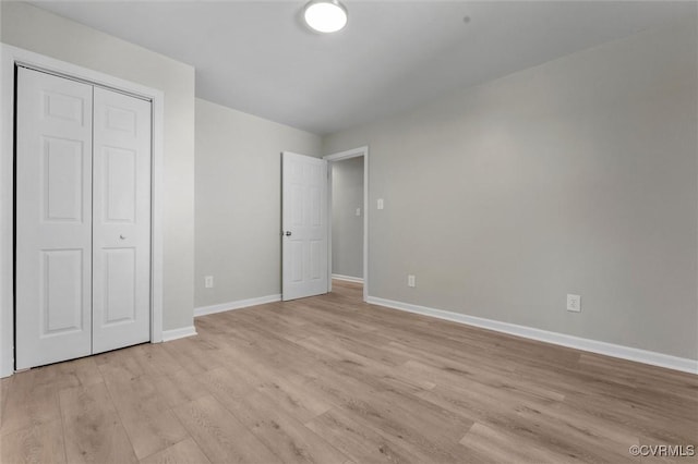 unfurnished bedroom with baseboards, light wood-style floors, and a closet