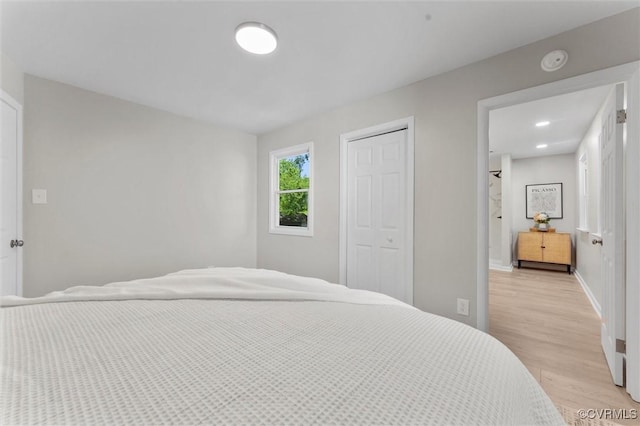 bedroom with light wood-style flooring, a closet, and baseboards