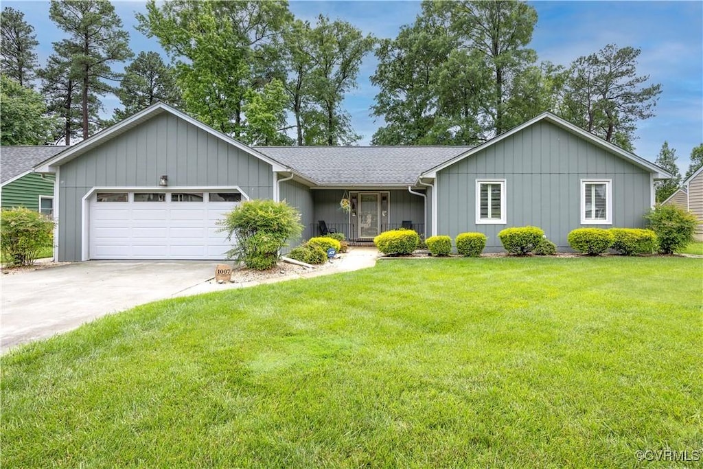 ranch-style home featuring a garage, driveway, a front yard, board and batten siding, and roof with shingles