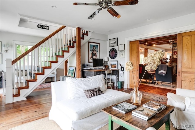 living area with wood finished floors, stairway, and ceiling fan