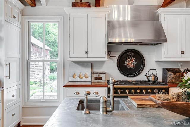 kitchen with wall chimney exhaust hood and white cabinets