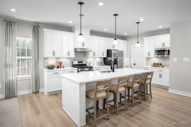 9 Abercrombie Dr, Chesterfield, VA 23838 - kitchen with stainless steel appliances, under cabinet range hood, backsplash, light wood finished floors, and an island with sink