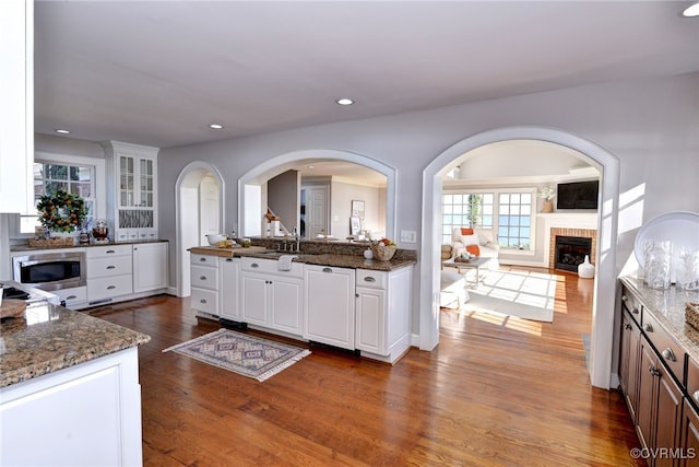 6454 Carmines Island Ln, Gloucester, VA 23072 - kitchen with a fireplace, dark wood finished floors, recessed lighting, white cabinets, and dark stone counters