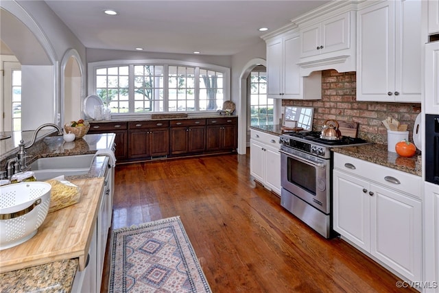 6454 Carmines Island Ln, Gloucester, VA 23072 - kitchen featuring high end stainless steel range, a sink, arched walkways, dark wood-style floors, and white cabinetry