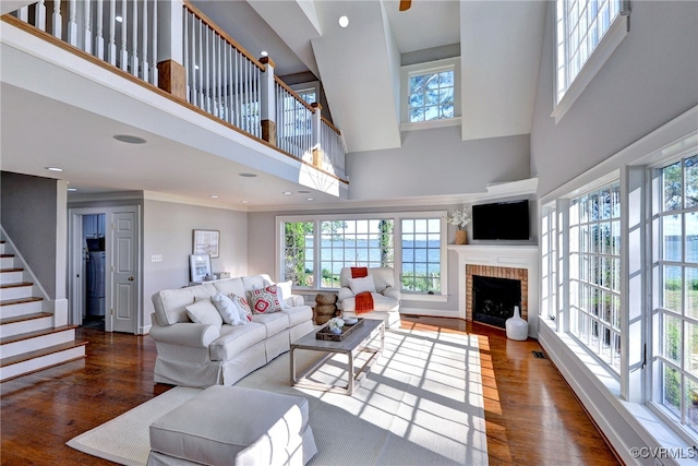 6454 Carmines Island Ln, Gloucester, VA 23072 - living room featuring wood finished floors, a towering ceiling, a brick fireplace, stairway, and recessed lighting
