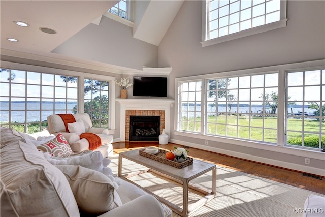 6454 Carmines Island Ln, Gloucester, VA 23072 - living area with a towering ceiling, a water view, a brick fireplace, wood finished floors, and baseboards