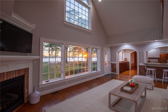 6454 Carmines Island Ln, Gloucester, VA 23072 - living area with high vaulted ceiling, arched walkways, light wood finished floors, a brick fireplace, and baseboards