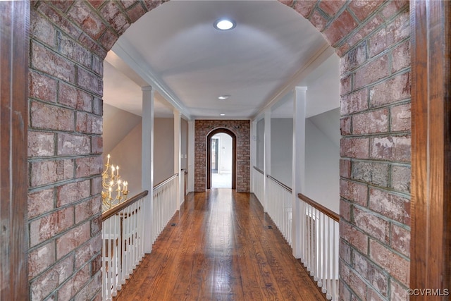6454 Carmines Island Ln, Gloucester, VA 23072 - hallway with arched walkways, wood-type flooring, brick wall, and a chandelier