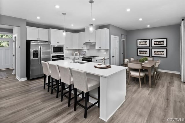 13 Abercrombie Dr, Chesterfield, VA 23838 - kitchen featuring stainless steel appliances, a sink, wall chimney exhaust hood, light wood finished floors, and backsplash