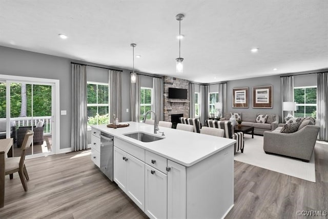 13 Abercrombie Dr, Chesterfield, VA 23838 - kitchen with a sink, stainless steel dishwasher, a stone fireplace, white cabinetry, and light wood-style flooring