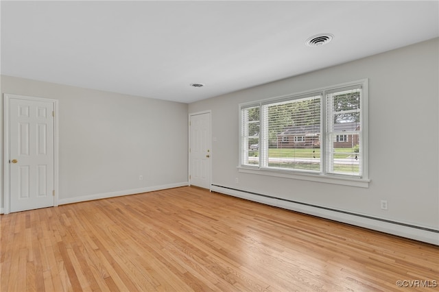 empty room with light wood-style flooring, a baseboard radiator, and baseboards