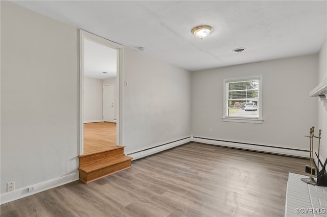 empty room featuring wood finished floors, baseboards, and a baseboard radiator