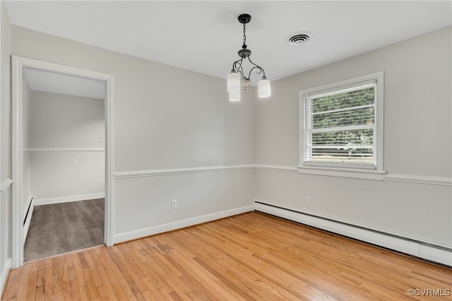 spare room with baseboard heating, light wood finished floors, and baseboards