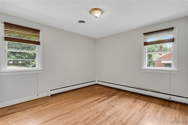 unfurnished room with light wood finished floors, a baseboard heating unit, and baseboards
