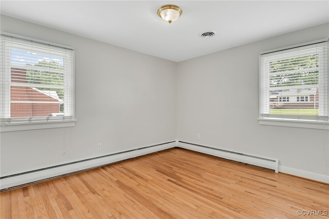 empty room featuring light wood finished floors, baseboards, and a baseboard radiator