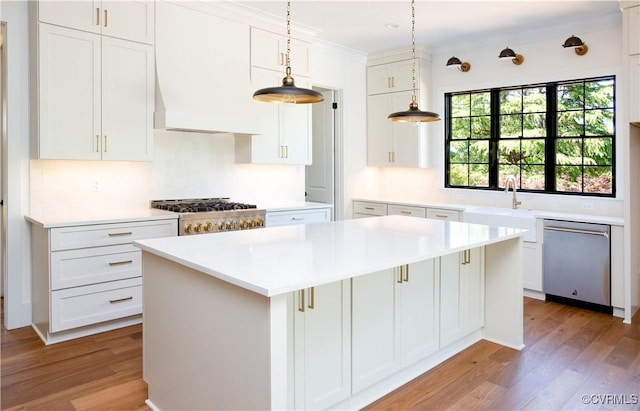 kitchen featuring dishwasher, light wood finished floors, a sink, a center island, and white cabinetry