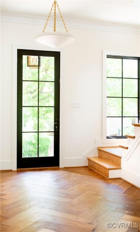entryway with stairs, healthy amount of natural light, ornamental molding, and baseboards