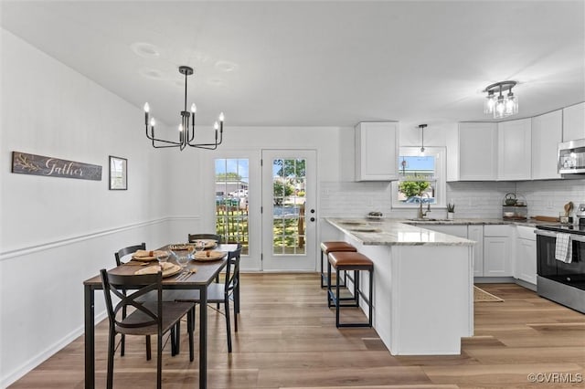1725 Porter St, Richmond, VA 23224 - kitchen featuring appliances with stainless steel finishes, a sink, white cabinets, a breakfast bar area, and a chandelier