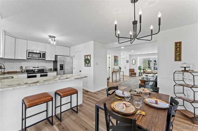 1725 Porter St, Richmond, VA 23224 - dining area with light wood-type flooring, a chandelier, and baseboards