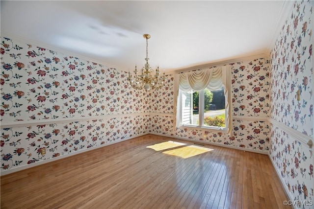 unfurnished dining area featuring wallpapered walls, ornamental molding, light wood finished floors, a chandelier, and baseboards