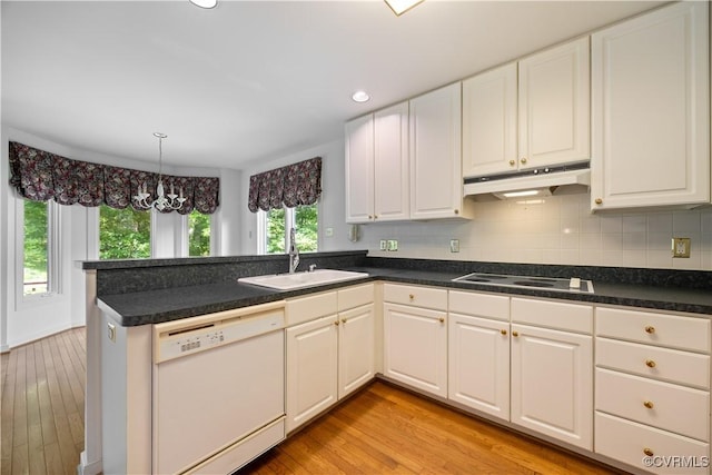 kitchen featuring white appliances, a sink, under cabinet range hood, a peninsula, and light wood-type flooring