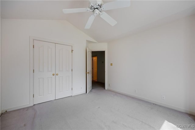 unfurnished bedroom featuring lofted ceiling, carpet, a closet, baseboards, and a ceiling fan